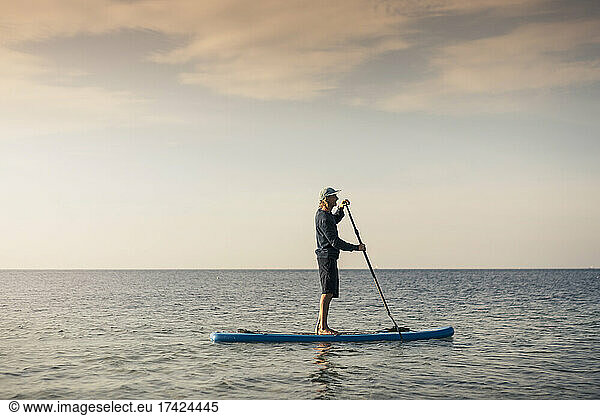 Male instructor paddleboarding in sea during summer vacation