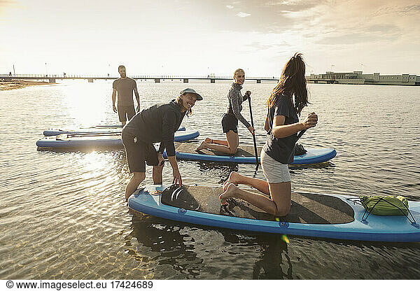 Male instructor teaching woman to paddleboard in sea