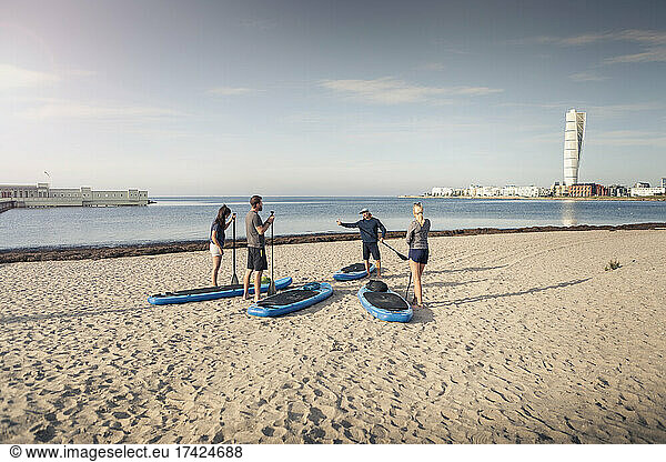 Male instructor training man and women at beach during vacation