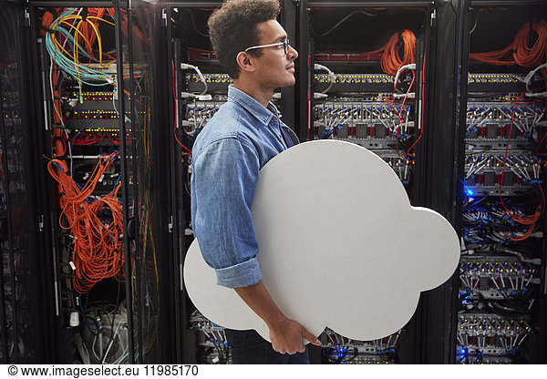 Male IT technician carrying cloud in server room  cloud computing