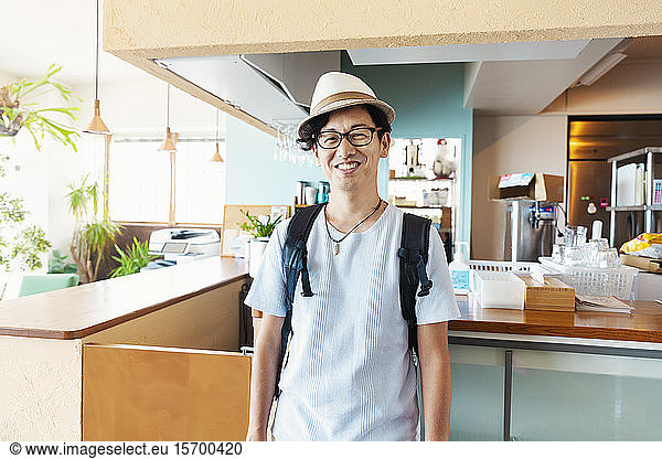 Male Japanese professional standing in a co-working space  smiling at camera.