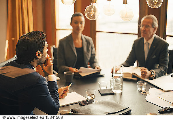 Male legal advisor discussing with colleagues in meeting at legal office