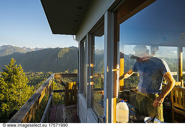Male making food inside Heybrook Fire Lookout Tower in the mountains