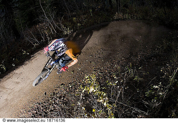 Male mountain biker on single track trail. Maneuvering a sharp turn on dirt packed trail. Helmet  gloves and fall leaves on the path.