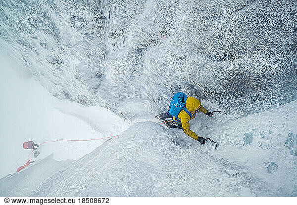 Male mountaineer climbing technical ice gully in cold temperatures