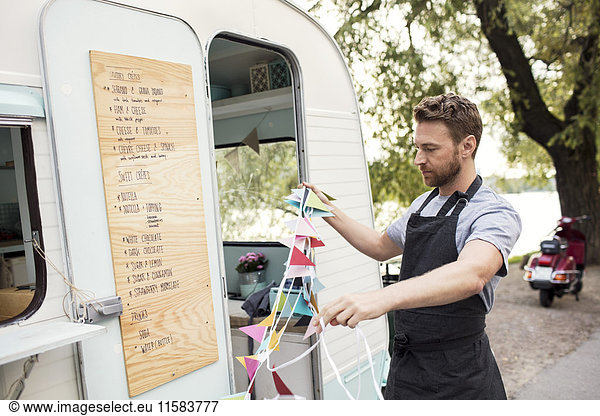 Male owner holding bunting flags outside food truck