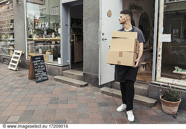 Male owner with boxes standing outside design studio