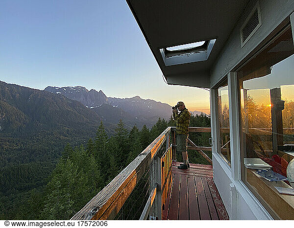 Male photographer taking photo from the deck of a fire lookout tower