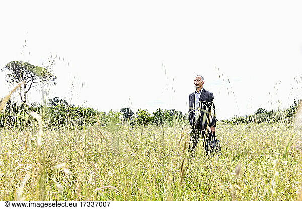 Male professional in businesswear standing in grassy field