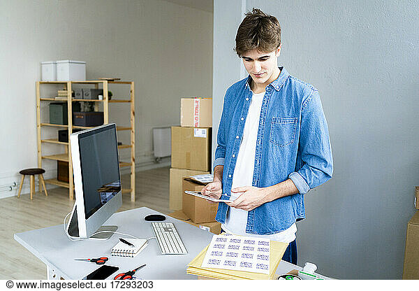 Male professional with digital tablet examining QR codes at desk in office