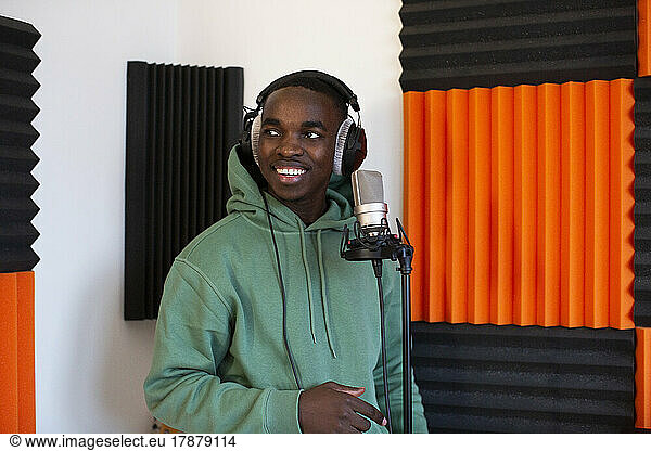 Male rapper with headphones standing in recording studio