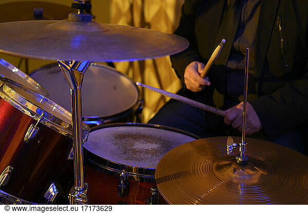 Male rock musician practicing with drums at studio