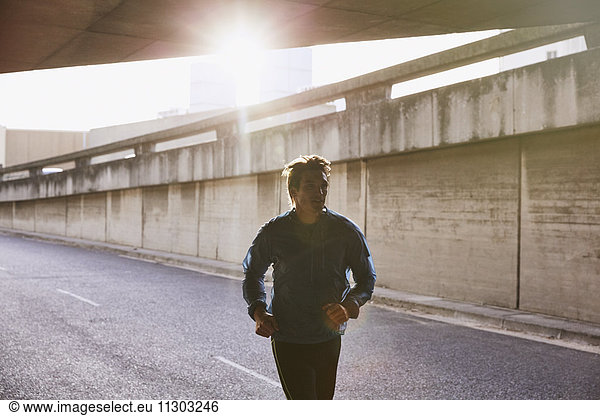 Male runner running into urban tunnel