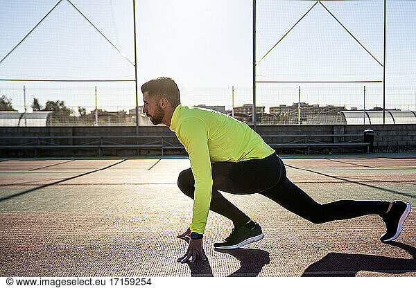 Male runner training at sports court during sunny day