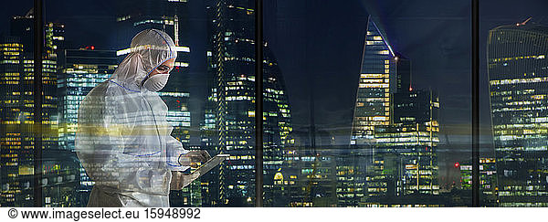 Male scientist in clean suit working late in city window