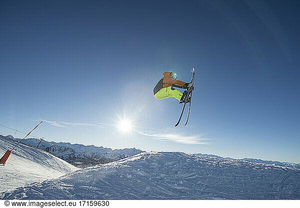 Male skier jumping against sky