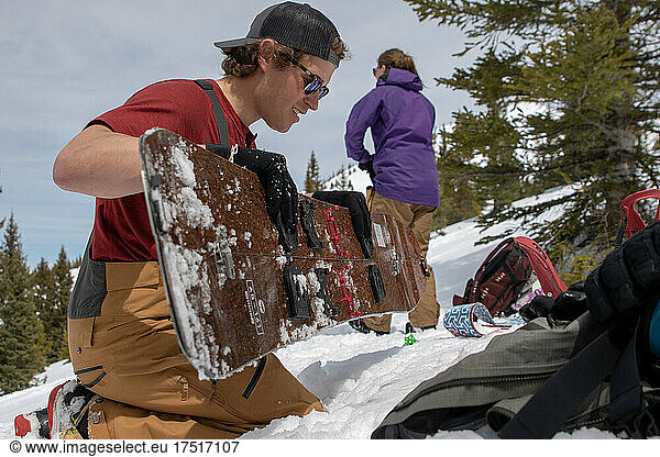 Male snowboarder assembles splitboard in the Colorado Backcountry