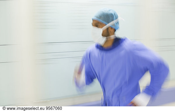 Male surgeon rushing through hospital corridor