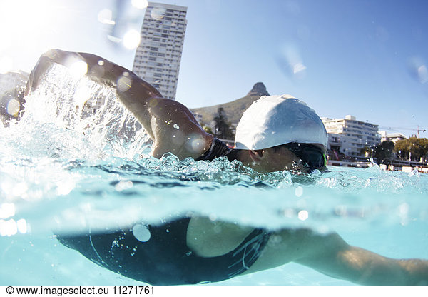 Male swimmer athlete swimming in sunny swimming pool