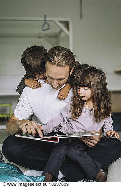 Male teacher reading story for children at day care center