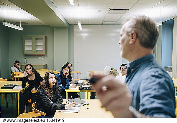 Male teacher teaching high school students in classroom