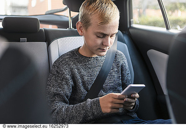 Male teenager using phone while sitting in car