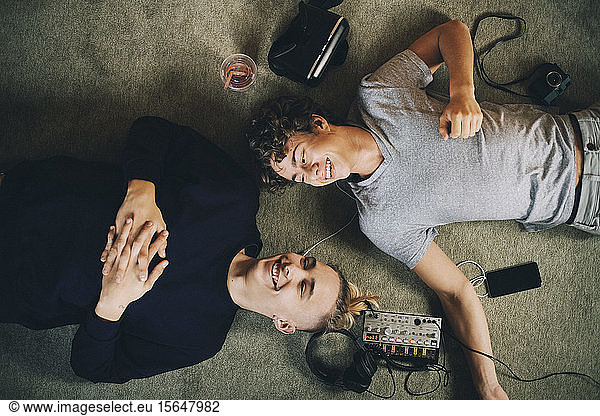 Male teenagers listening music while lying together on carpet at home