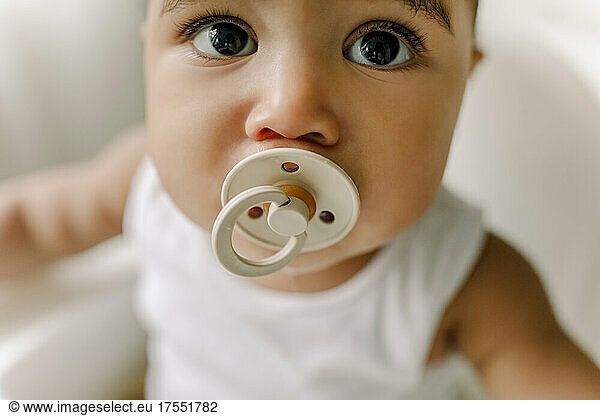 Male toddler with pacifier at home