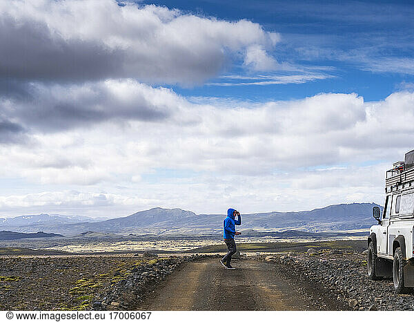 Male tourist walking on dirt road towards off road vehicle against sky  Lakagigar  Iceland
