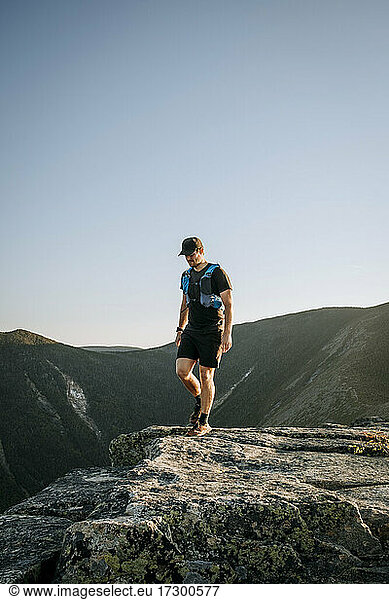 Male trail runner hikes on granite in White Mountains  New Hampshire