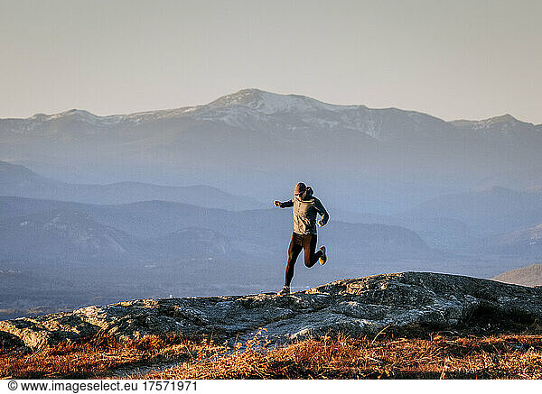 Male trail runner runs along summit of Foss Mountain  New Hampshire