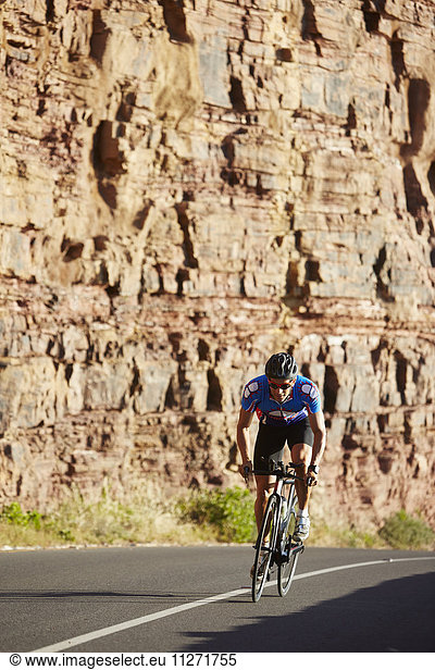 Male triathlete cyclist cycling on sunny road