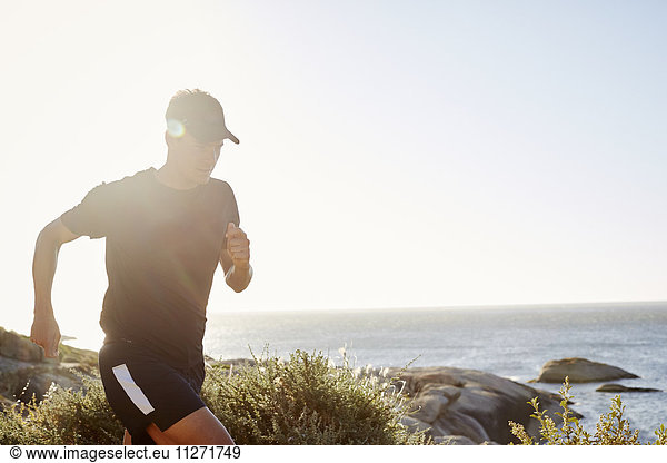 Male triathlete runner running along ocean