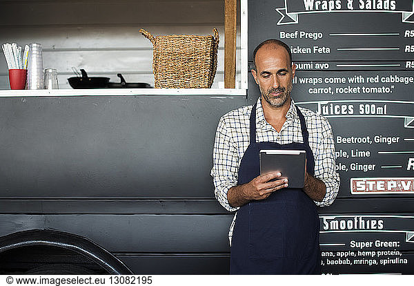 Male vendor using tablet computer while standing against food truck