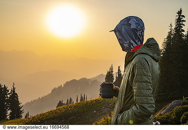 Male with a beverage watching the sunset behind wildfire smoke