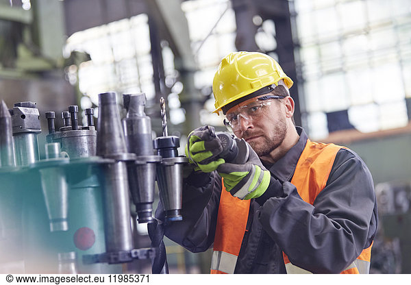 Male worker examining steel parts in factory