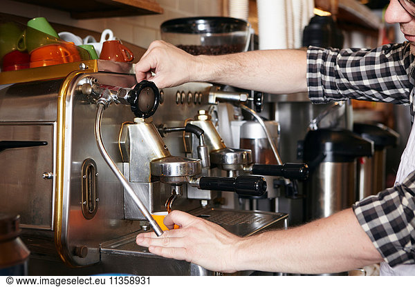 Male worker in bakery  using coffee machine  close-up