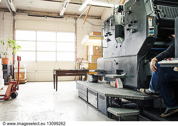 Male worker operating printing machine at workshop