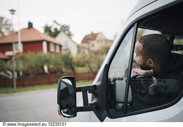 Male worker sitting in delivery van at city