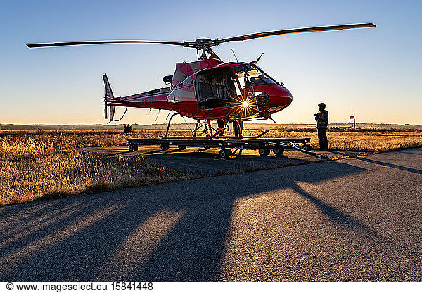 Man about to board helicopter and sunrise light shining through.
