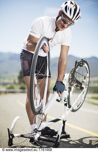 Man adjusting bicycle on rural road