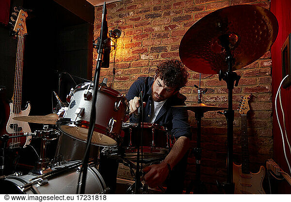 Man adjusting drum set in music studio