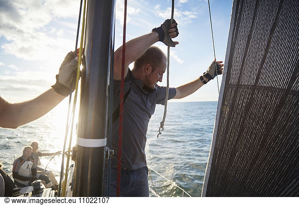 Man adjusting sailing rigging on sailboat