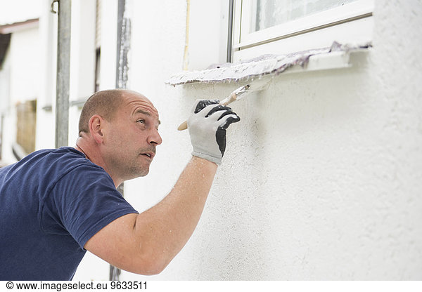 Man alone painting brush window wall house