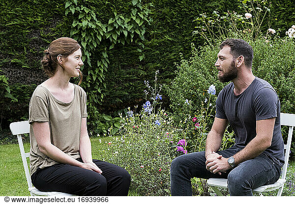Man and a therapist seated in a garden  talking.