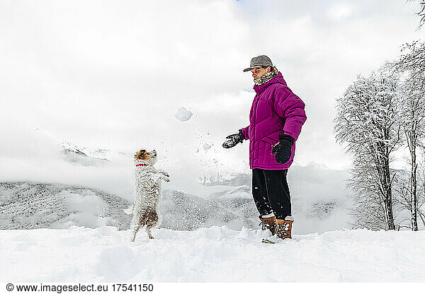 Man and dog playing with snow