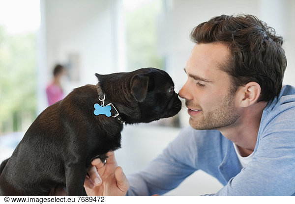 Man and dog touching noses indoors