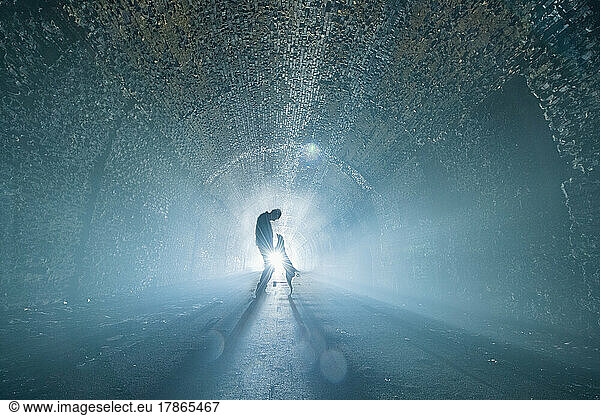 Man and Dog Walk Down Backlit Tunnel