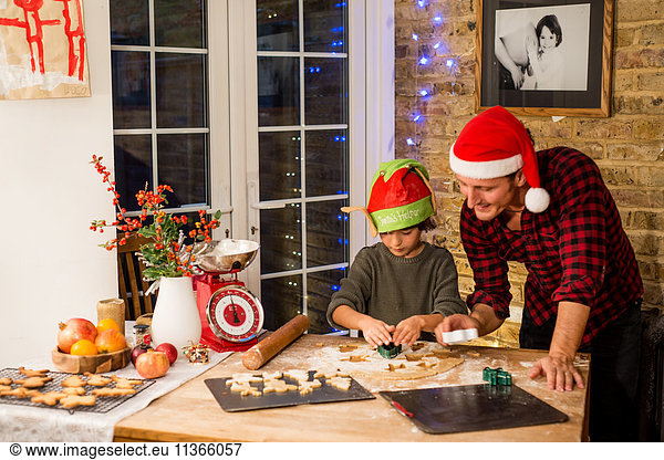 Man and son preparing Christmas cookies at kitchen counter
