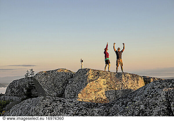 Man and woman celebrate reaching mountain summit while hiking  Maine